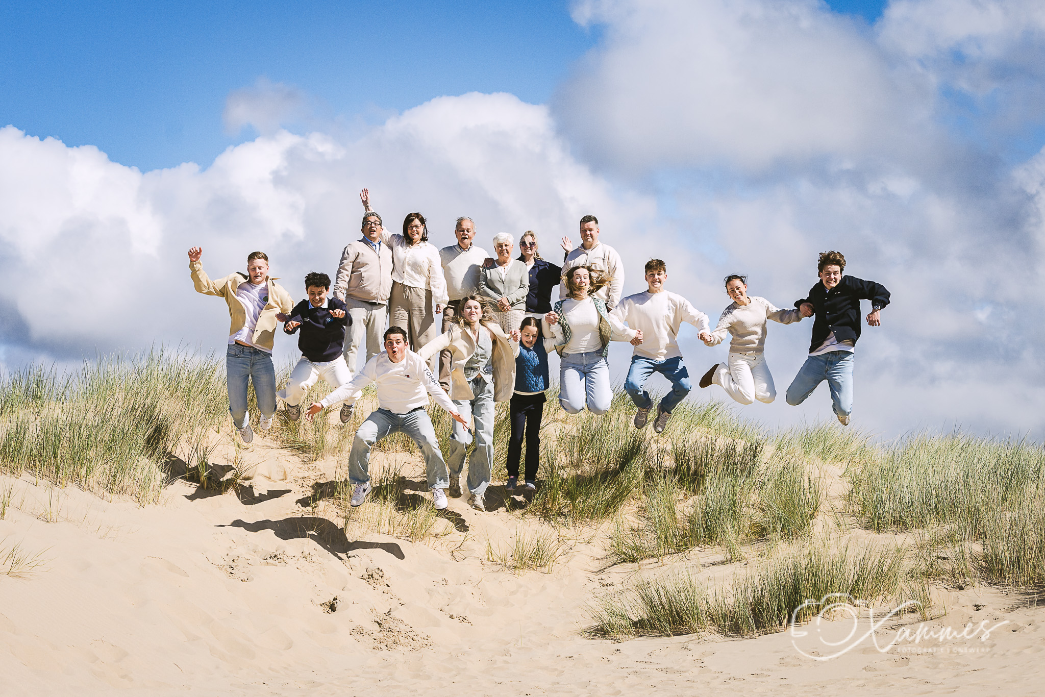 Grote familie springt samen in de duinen tijdens een spontane familiefotoshoot aan zee